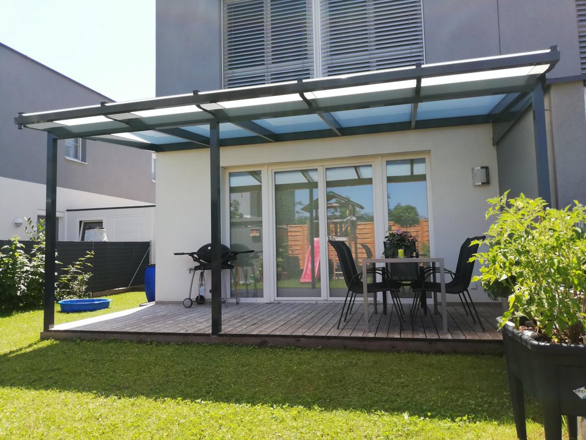 BAUMANN Glas graues Terrassendach mitten im grünem Garten BAUMANN Glas Terrassendach mitten im grünem Garten